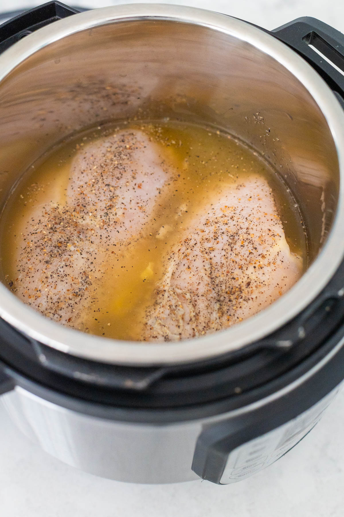The chicken breasts have been set into the Instant Pot with the chicken stock.