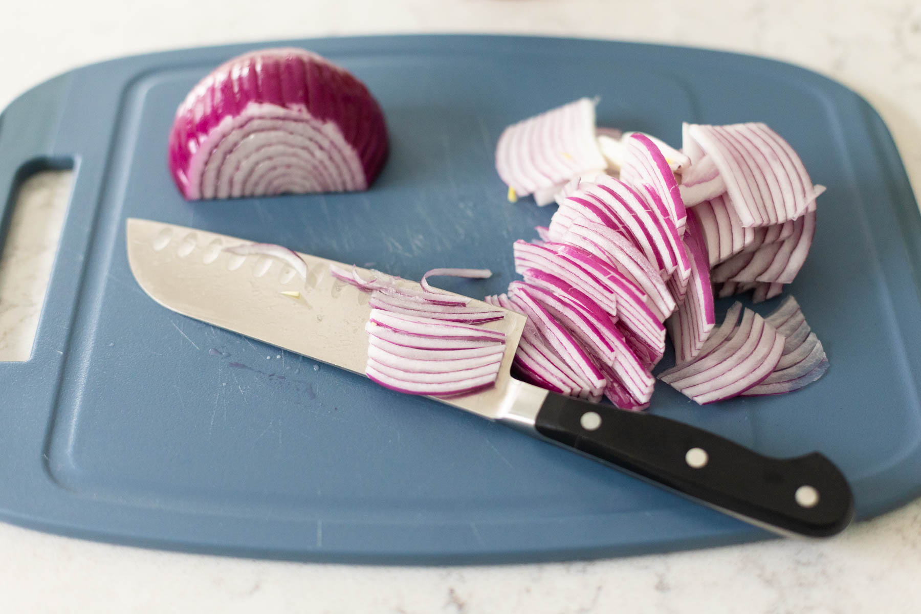 The onion has been cut on a cutting board with a large chef knife.