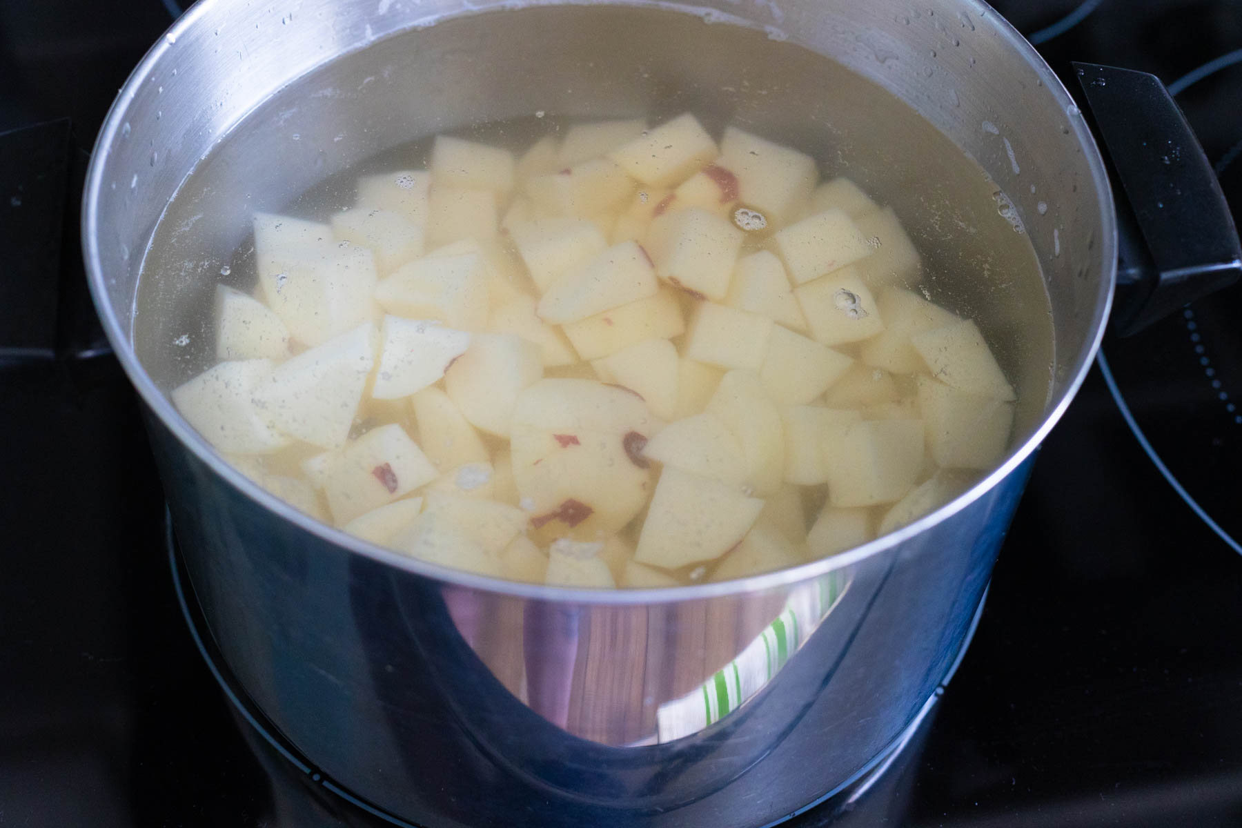 The chopped potatoes are resting in a pot of cold water.