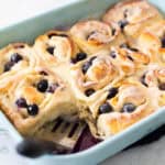 A blue baking dish filled with blueberry rolls.