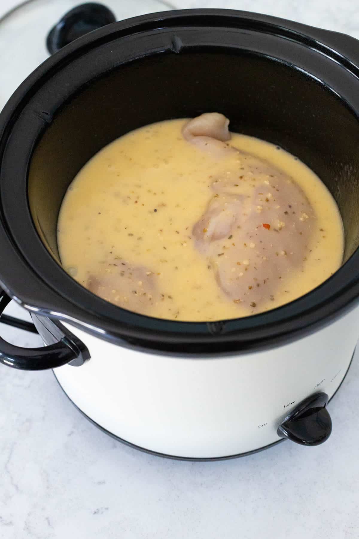 The chicken breasts and Italian dressing are in the slowcooker pot.