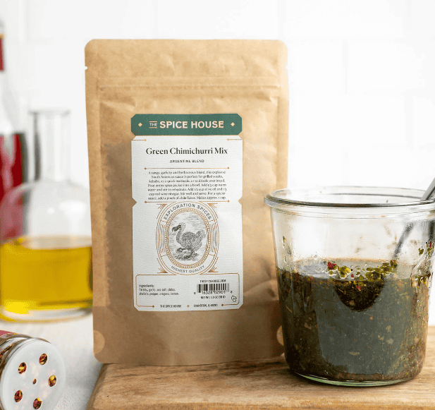 A packet of freeze-dried chimichurri seasonings next to the prepared sauce in a cup.