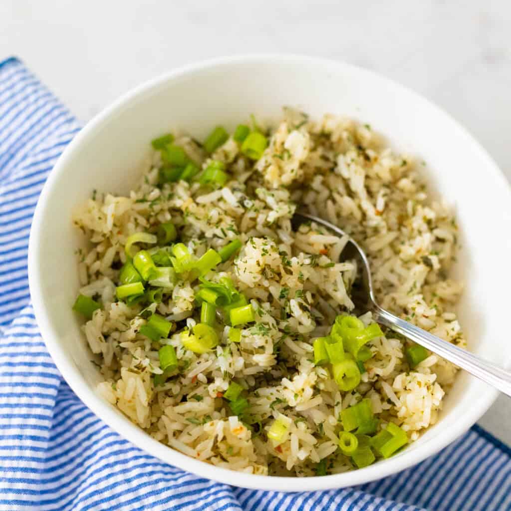 A bowl of chimichurri rice has green onions sprinkled over the top.