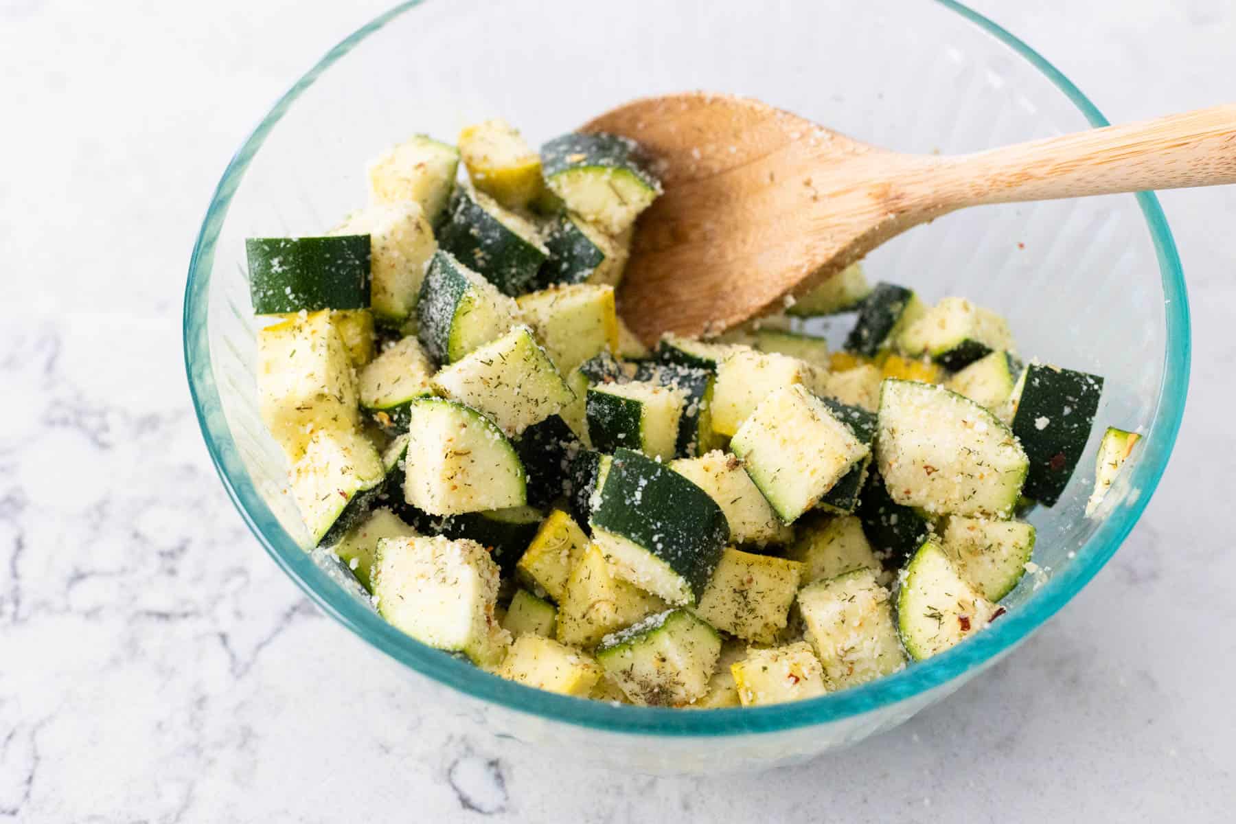 The grated parmesan now coats the vegetables in the bowl.