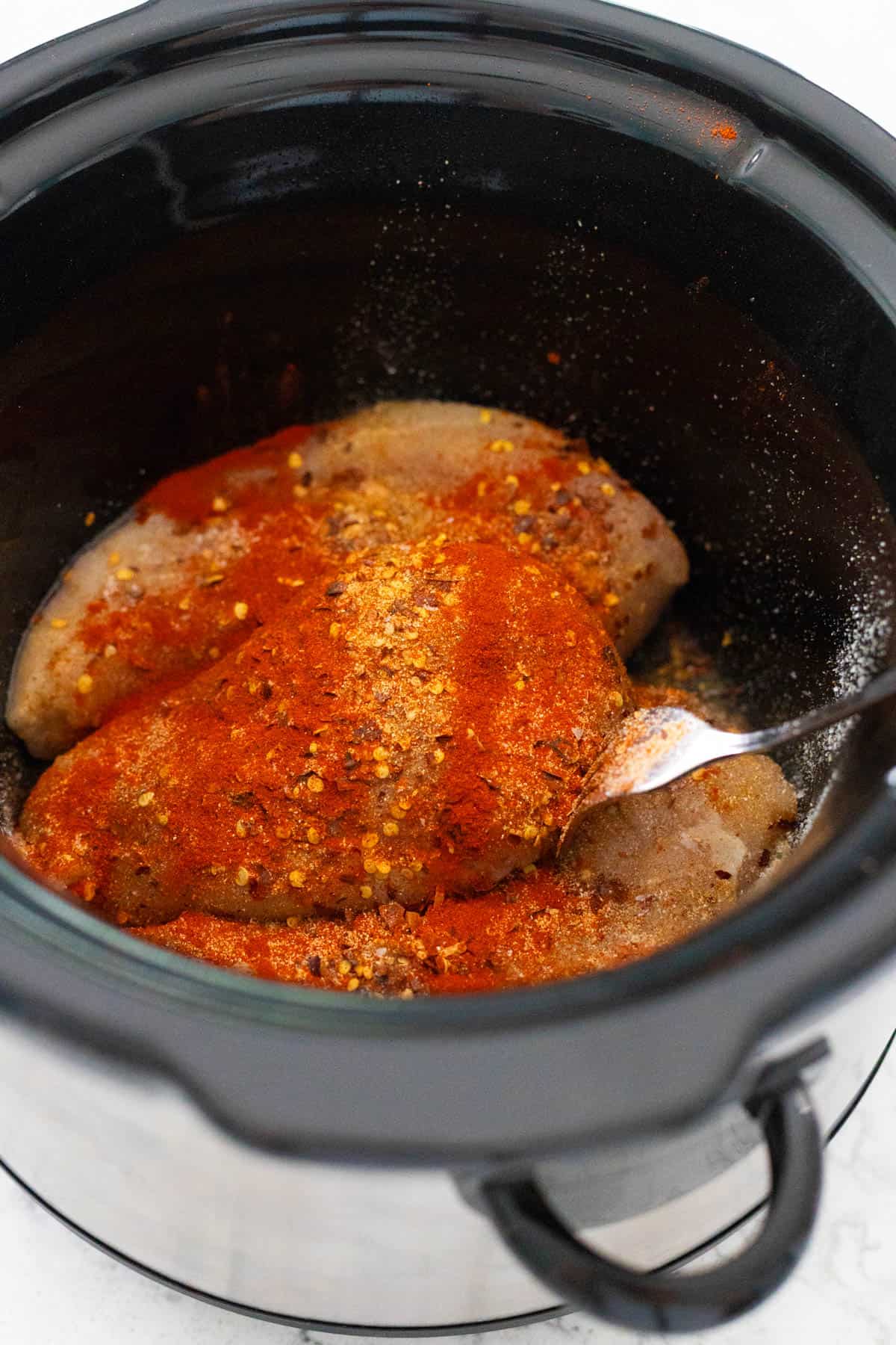 The chicken is in the Crockpot covered in dry seasoning.